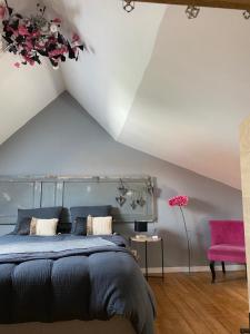 a bedroom with a bed and a pink chair at Le Refuge des Etoiles Gîte et Spa in Zutkerque