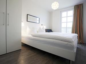 ein weißes Schlafzimmer mit einem großen Bett und einem Fenster in der Unterkunft Residenz am Balmer See - BS 55 mit Wellnessbereich in Balm