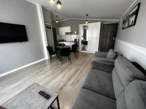 a living room with a gray couch and a table at Apartamenty BLAST nad morzem Chłopy in Chłopy