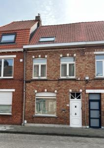 a brick house with a white door and windows at MORI in Bruges