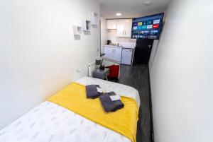 バーミンガムにあるModern cosy studio availableの小さなお部屋で、ベッド1台(黄色の毛布付)が備わります。