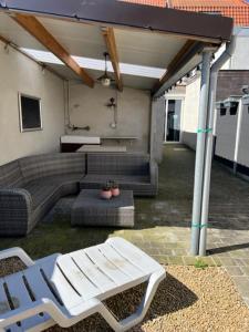 eine Terrasse mit einem Sofa, einem Tisch und Stühlen in der Unterkunft MORI in Brügge