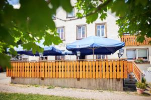 une clôture avec des parasols bleus devant un bâtiment dans l'établissement Gasthof & Pension Steppacher, à Friedenweiler