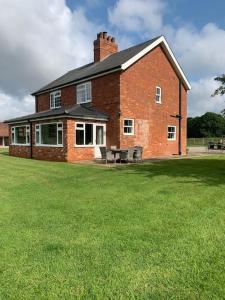 a large brick building with a picnic table in a yard at Bainvalley Cottages peaceful South Cottage in Lincolnshire