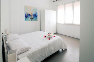 a white bedroom with a bed with a stuffed animal on it at Appartamenti Gherbin in Lido di Jesolo