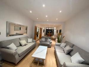 a living room with two couches and a table at Beautiful large 6 bedroom house up to 14 people in Hendon