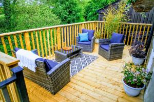 a wooden deck with wicker chairs and a table at Mourne Magic House-Riverside luxury in Newcastle in Newcastle