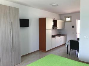 una cocina con armarios blancos y una mesa con una alfombra verde en Pescasubacquea, en Crotone