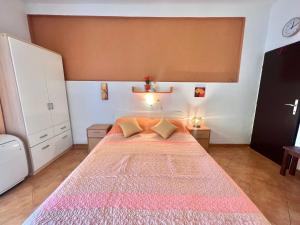 een slaapkamer met een groot bed en een roze deken bij Apartmani Zeleni Raj in Dramalj