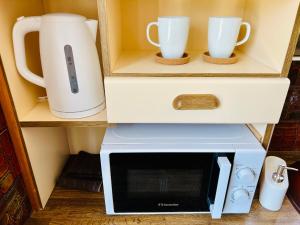 a microwave and two cups on a shelf at Gazonia Family Estate in Skala Kefalonias