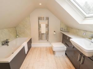 a bathroom with a sink and a tub and a toilet at Lee House Cottage in Cheddleton
