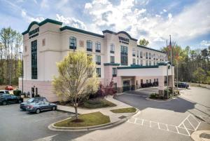 a large white building with a parking lot at Wingate by Wyndham State Arena Raleigh/Cary Hotel in Raleigh
