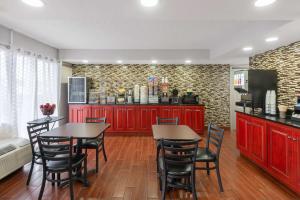 una cocina con armarios rojos y 2 mesas y sillas en Days Inn by Wyndham Charlottesville/University Area, en Charlottesville