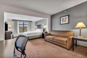 Wingate by Wyndham State Arena Raleigh/Cary Hotel في رالي: غرفه فندقيه بسرير واريكه