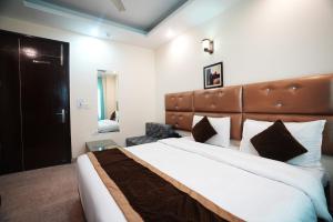 a bedroom with a large bed with a brown headboard at Hotel S & B East Inn - Patel Nagar in New Delhi
