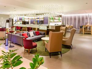 a lobby with couches and chairs and a restaurant at Novotel Sao Paulo Center Norte in Sao Paulo
