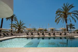 una piscina con sillas y sombrillas y palmeras en Hotel Palma Bellver , Affiliated by Meliá, en Palma de Mallorca