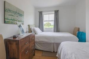 a bedroom with two beds and a dresser and a window at Bainvalley Cottages, Beautiful North Cottage in Lincolnshire