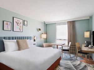 a hotel room with a large bed and a desk at Mercure Amiens Cathédrale in Amiens