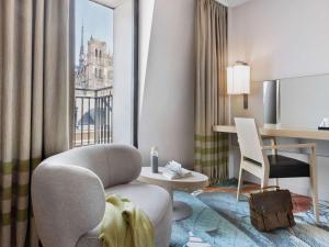 a hotel room with a chair and a desk and a window at Mercure Amiens Cathédrale in Amiens