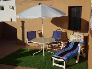 una mesa, sillas y una sombrilla en una habitación en Apartment Severo Ochoa, en Puerto del Rosario