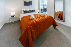 una camera con un letto e una coperta arancione di City Lights Retreat with Carpark 2 Bed 2 Bath a Christchurch