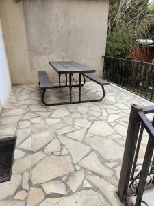 a picnic table and bench on a stone patio at Hôtel Les 4 Chênes in Pontault-Combault