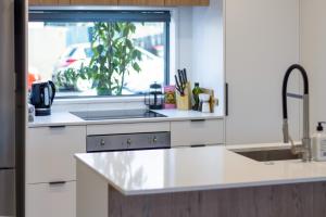 een witte keuken met een wastafel en een raam bij City Lights Retreat with Carpark 2 Bed 2 Bath in Christchurch