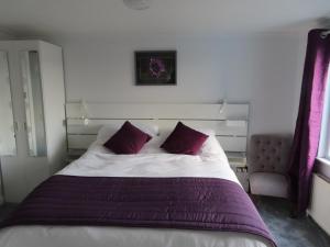 um quarto com uma cama grande e almofadas roxas em Barr Hill Woods B&B em Kirkcudbright