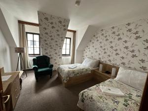 Cette chambre d'hôtel comprend deux lits et une chaise verte. dans l'établissement Hotel Radnice, à Liberec