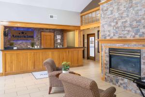 a living room with a fireplace and chairs at AmericInn by Wyndham Cedar Rapids North in Cedar Rapids