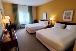 a hotel room with two beds and a television at Wingate by Wyndham Uniontown in Uniontown