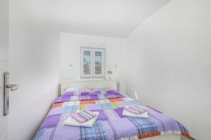 a white bedroom with a purple bed with two pillows at Nice apartment with balcony very close to the sea in Klimno