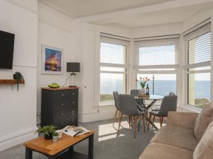 a living room with a couch and a table with chairs at Tir a Mor in Pwllheli