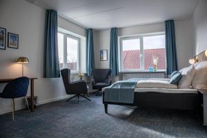 a bedroom with a bed and a desk and chairs at Hotel Phønix Hjørring in Hjørring