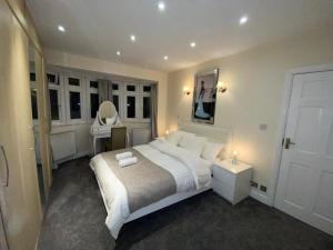 sypialnia z dużym białym łóżkiem i lustrem w obiekcie Beautiful large 6 bedroom house up to 14 people w mieście Hendon
