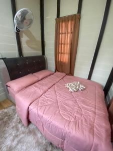 een roze bed met een roze dekbed in een kamer bij Sue Cottage Homestay in Jertih