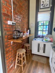eine Küche mit einer Backsteinwand und einer Theke mit Hockern in der Unterkunft Sue Cottage Homestay in Jertih