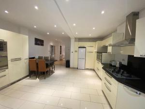 a kitchen with white cabinets and a table in it at Beautiful large 6 bedroom house up to 14 people in Hendon