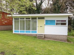 a white and blue garage with a grass yard at 107 Kings Chalet Park in Cromer +14 photos