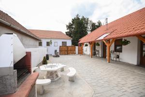 a patio with two benches and a table and a building at Nana’s Vendégház in Mád