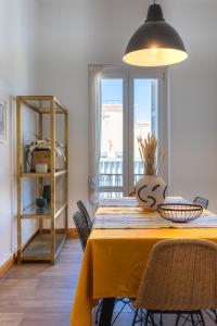 una sala da pranzo con tavolo giallo, sedie e finestra di Dimora di Stile a Città di Corfù