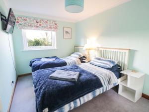 a bedroom with two beds and a window at Millbrook Cottage in Dalbeattie