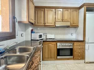 a kitchen with wooden cabinets and a stainless steel sink at Museu Baixos in L'Escala