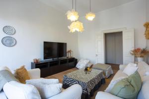a living room with white furniture and a flat screen tv at Dimora di Stile in Corfu Town