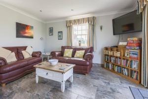 a living room with leather couches and a tv at Bainvalley Cottages - The Shamba, sleeps 4 in Lincolnshire