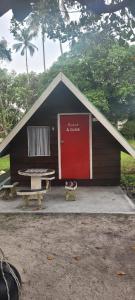 a small house with a red door and a picnic table at Villa Maya in Kampung Mawar