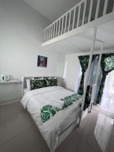 Dormitorio blanco con cama con almohadas verdes en Villa Maya en Kampung Mawar