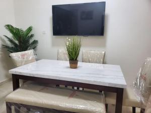شقة جمان طيبة Joman Taibah Apartment في المدينة المنورة: طاولة وكراسي مع تلفزيون على الحائط