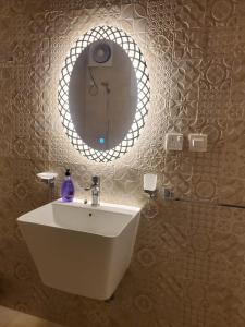 شقة جمان طيبة Joman Taibah Apartment في المدينة المنورة: حمام مع حوض أبيض ومرآة
